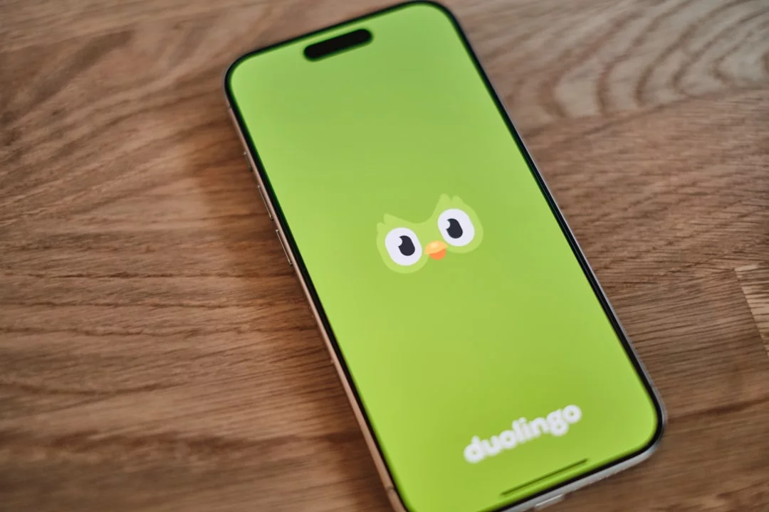 Duolingo vs Babbel vs Pimsleur: Which App Is Best in 2026? Green phone with a smiling face, illustrating how to pick the best language learning apps free in 10 minutes
