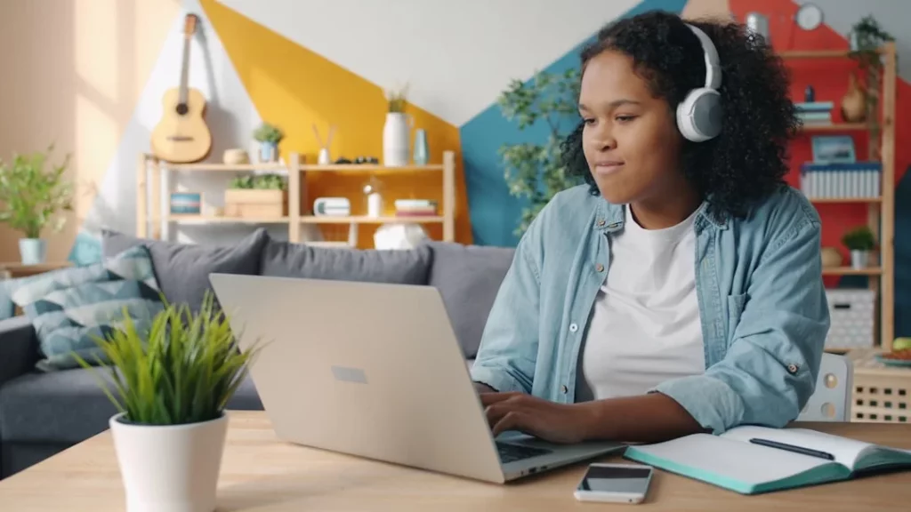 Binaural Beats vs Lo-fi vs Silence for Focus Young woman wearing headphones at her laptop, exploring binaural beats for studying at her desk