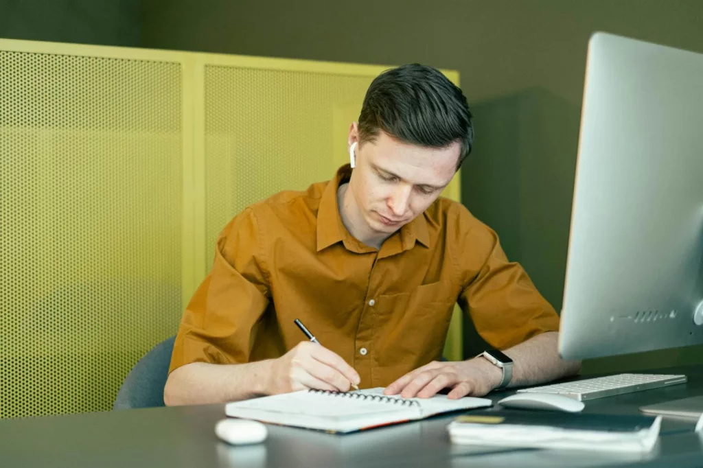 Student taking notes at a desk while comparing blurting method vs active recall study techniques