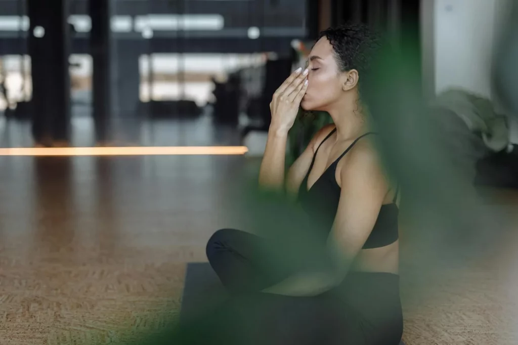 7 Evidence-Based Breathing Exercises for Stress and Focus Woman practicing yoga indoors with eyes closed, demonstrating breathing exercises for beginners and relaxation