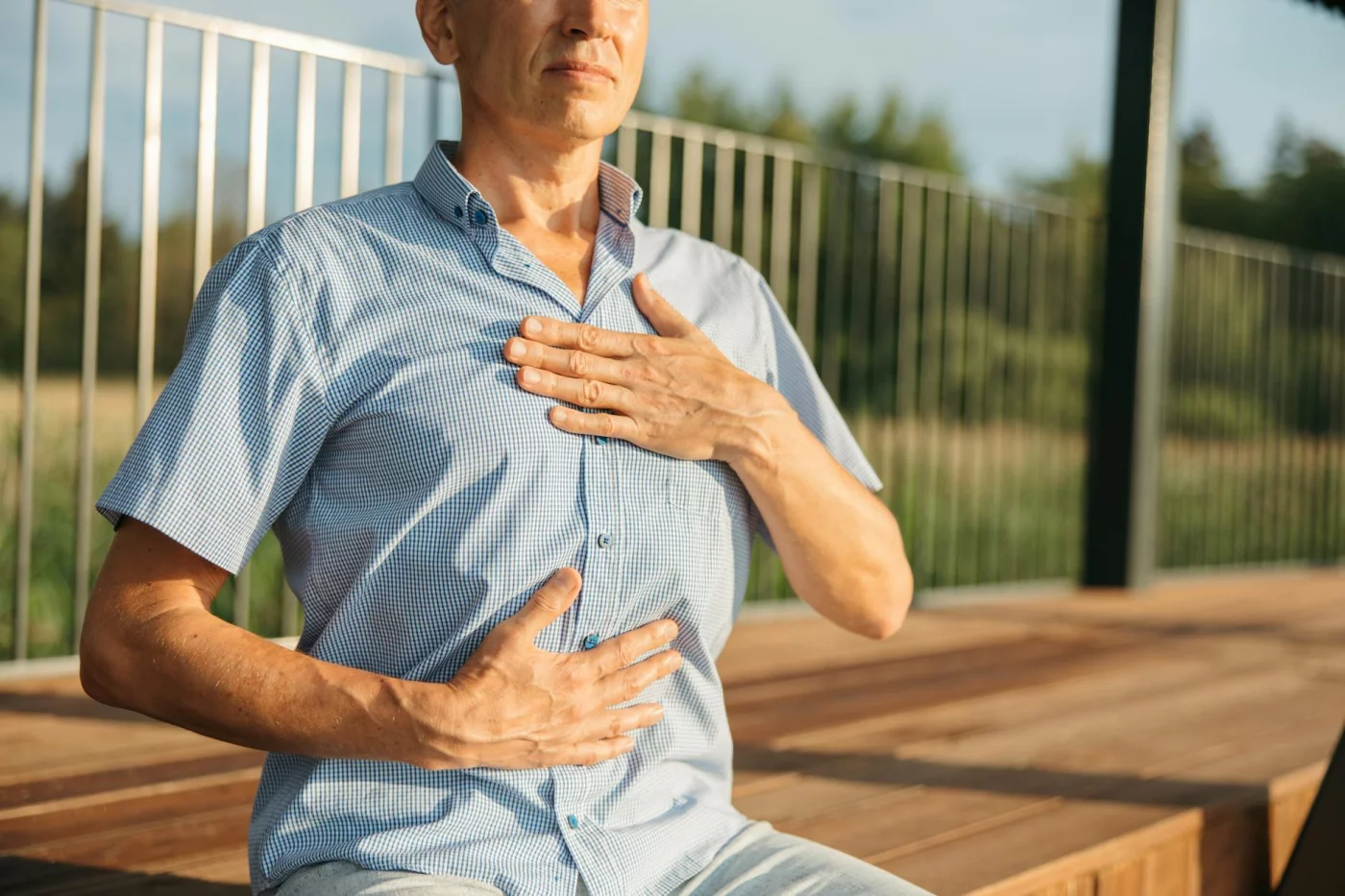 7 Evidence-Based Breathing Exercises for Stress and Focus Man practicing breathing exercises for beginners outdoors with hands on chest and abdomen