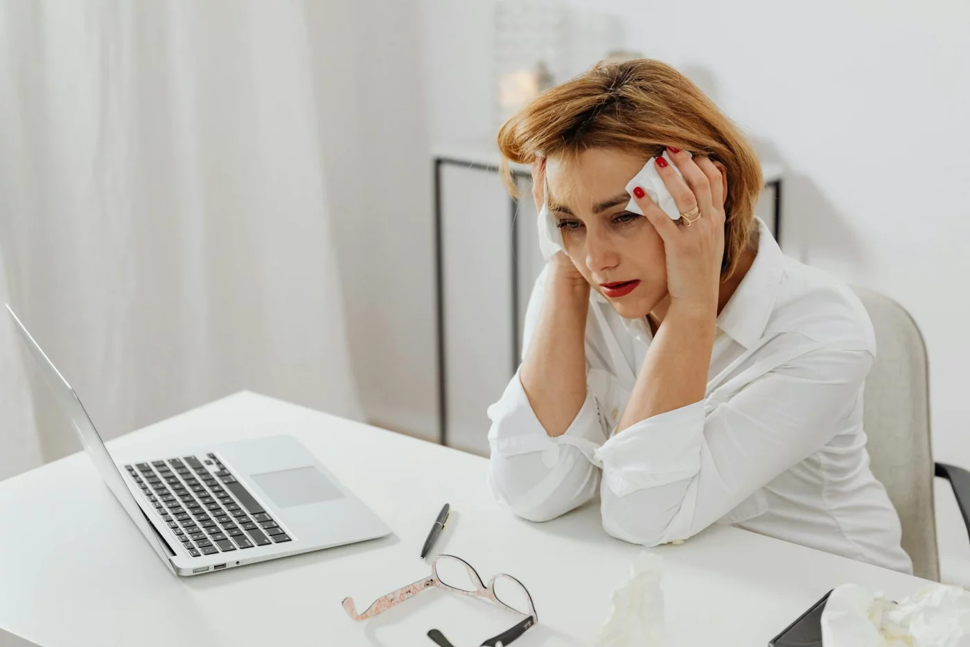 Woman in distress at her office desk with tissues and a laptop, contrasting acute stress with chronic stress examples
