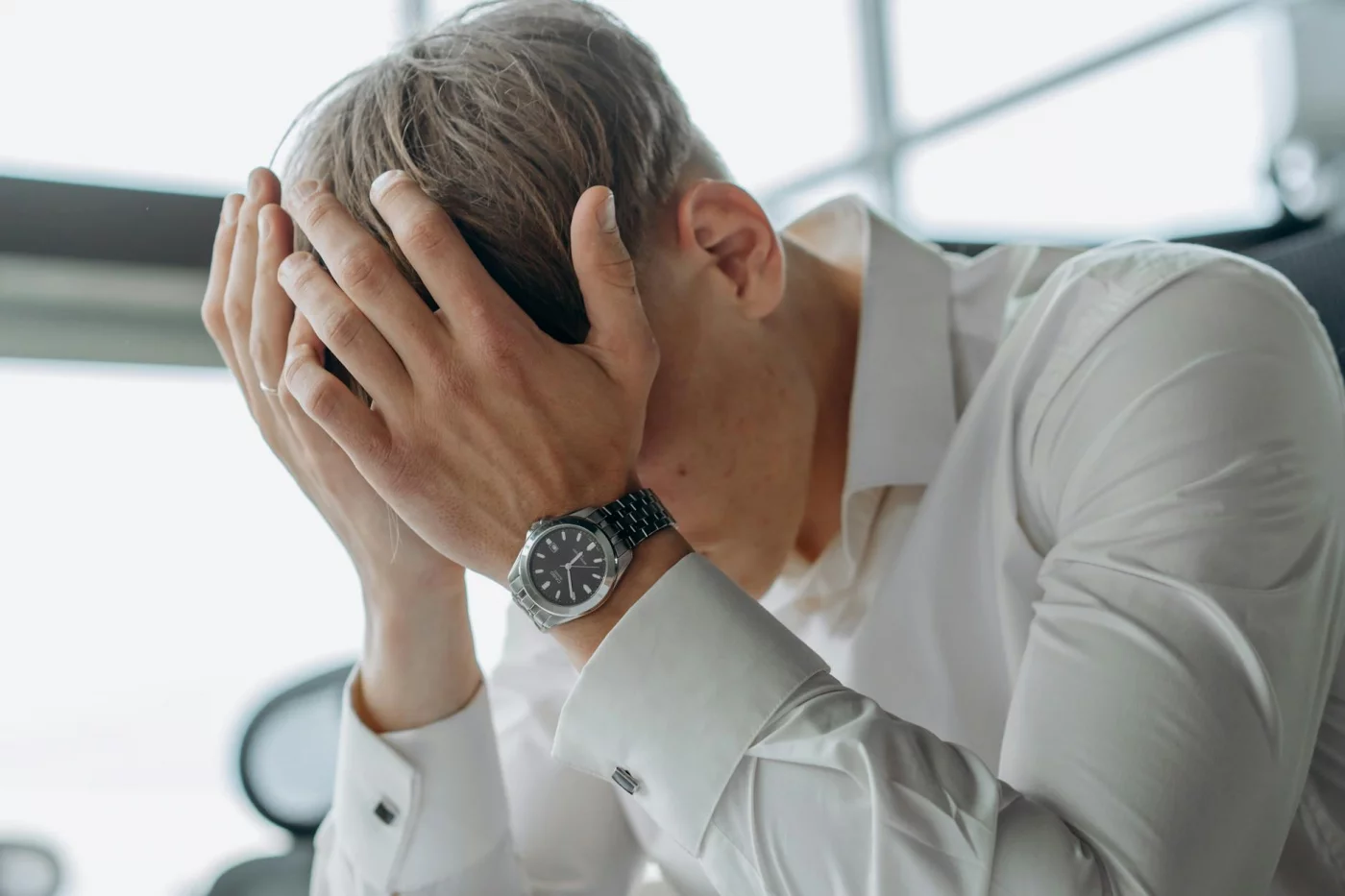 Business professional with head in hands showing fatigue, illustrating chronic stress examples becoming harder to ignore