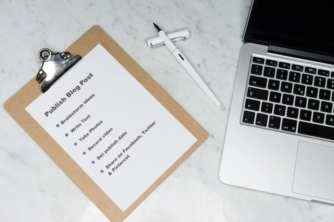 White printer paper beside a silver MacBook displaying a deep work checklist for focused planning