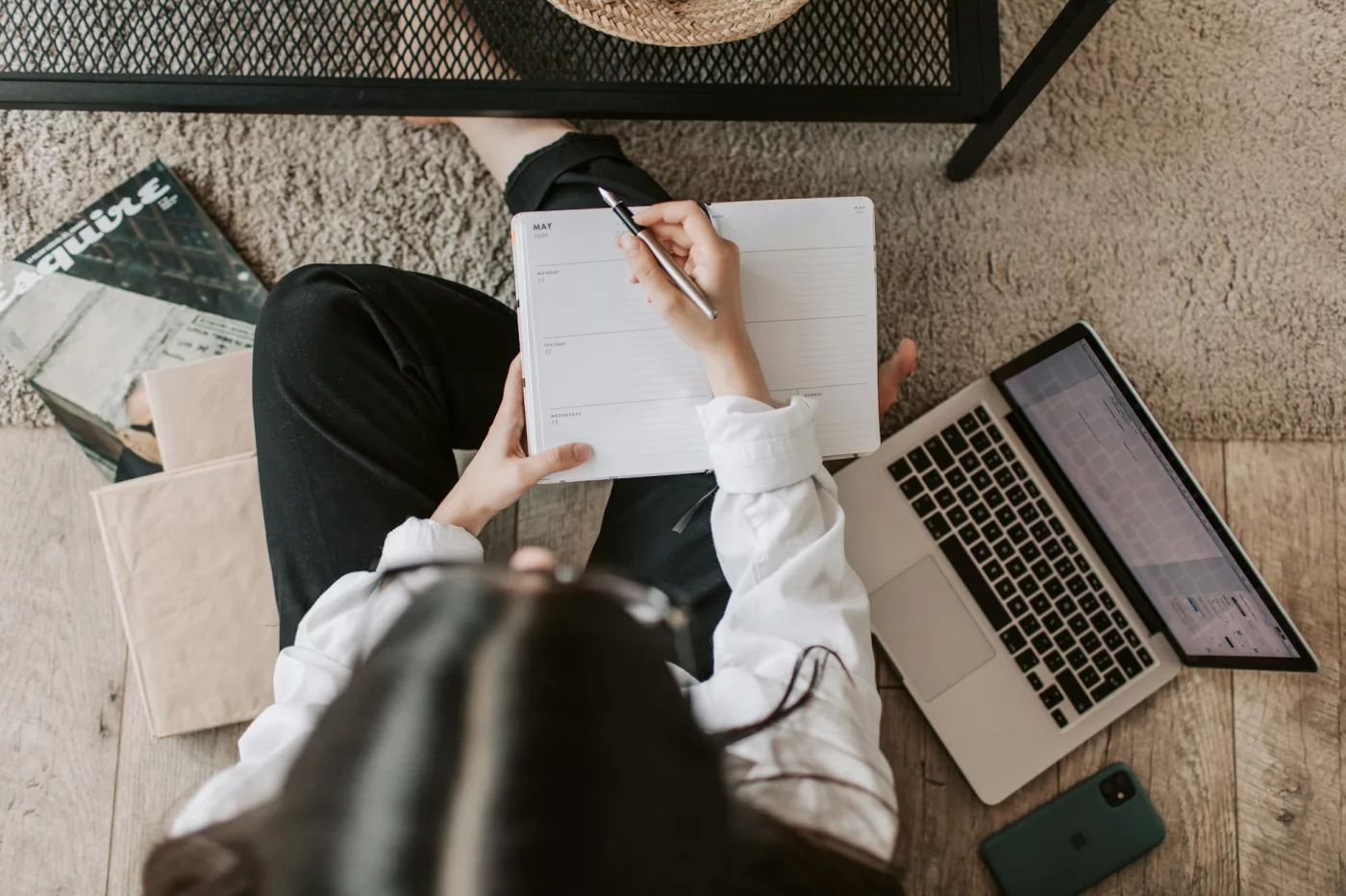 Woman planning attention warm-up rituals in a notebook with laptop and phone, using a deep work checklist