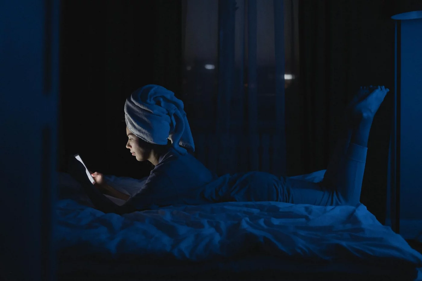 Blue Light and Sleep: How to Protect Your Brain at Night Woman in bed using her phone at night, showing how does blue light affect sleep quality and brain alertness