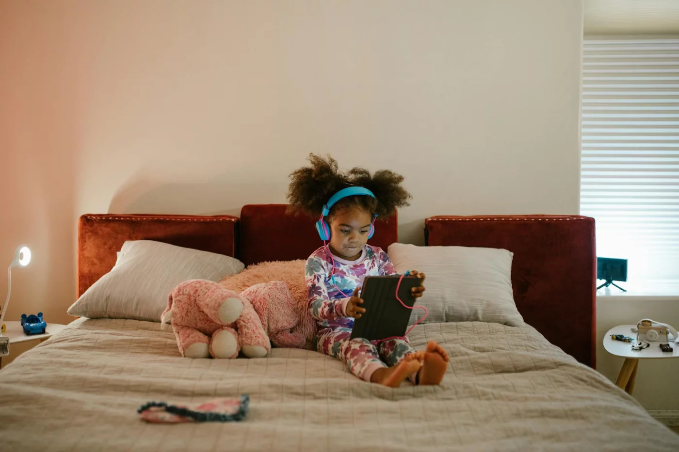 Blue Light and Sleep: How to Protect Your Brain at Night Girl in colorful pajamas using a tablet in bed, illustrating does blue light affect sleep quality