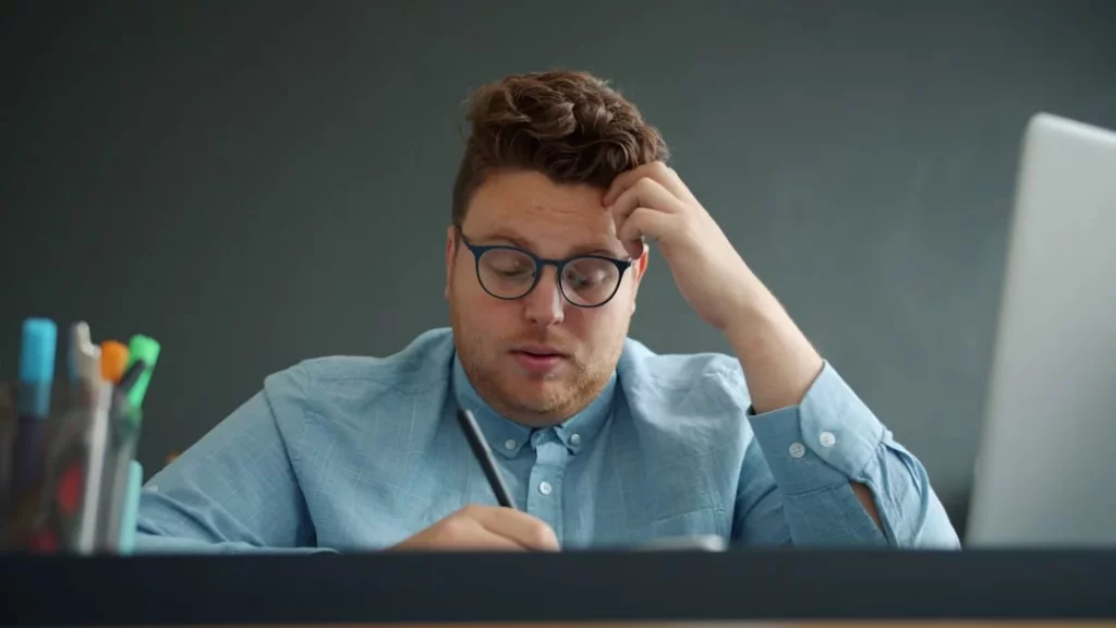 Man with glasses looking stressed at his desk, illustrating how does stress affect memory recall at work