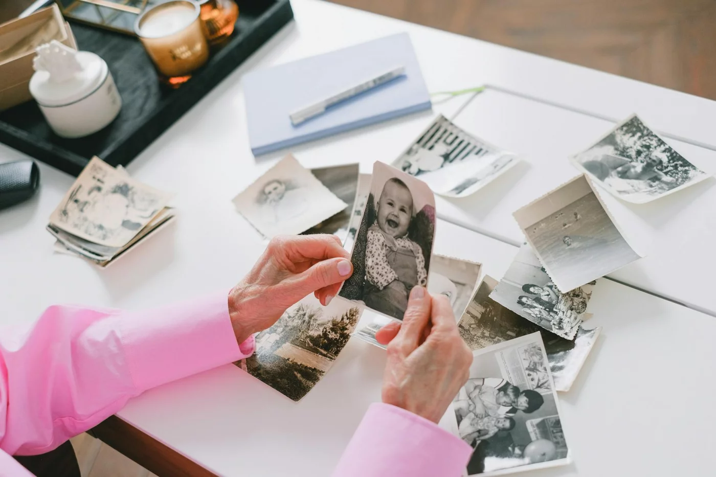 Face Blindness Test Meaning: How to Read Scores and What to Do Next Person in a pink shirt sorting old family photos, illustrating face blindness examples in everyday life