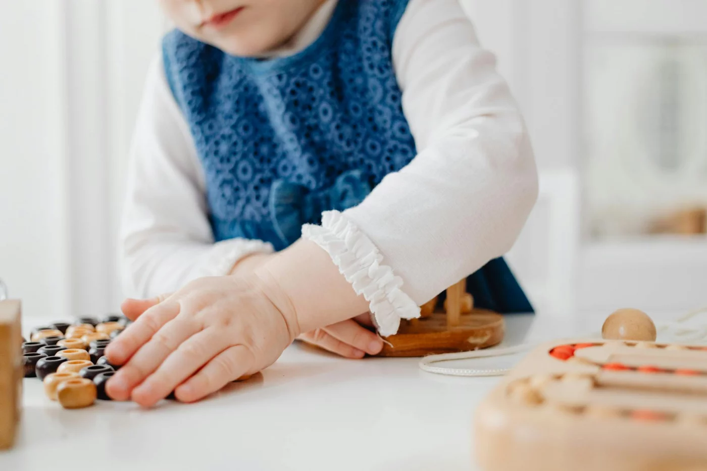 Fine Motor Skills vs Gross Motor Skills: 7 Proven Ways Adults Learn Faster Child playing with wooden educational toys, showing fine motor skills vs gross motor skills through hands-on learning