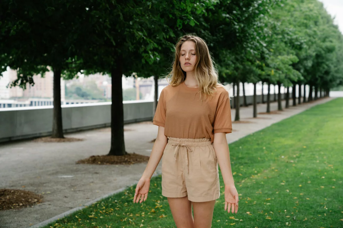Grounding Techniques for Sudden Anxiety Spikes in Public Woman practicing grounding techniques for overthinking while standing calmly with eyes closed in a green park