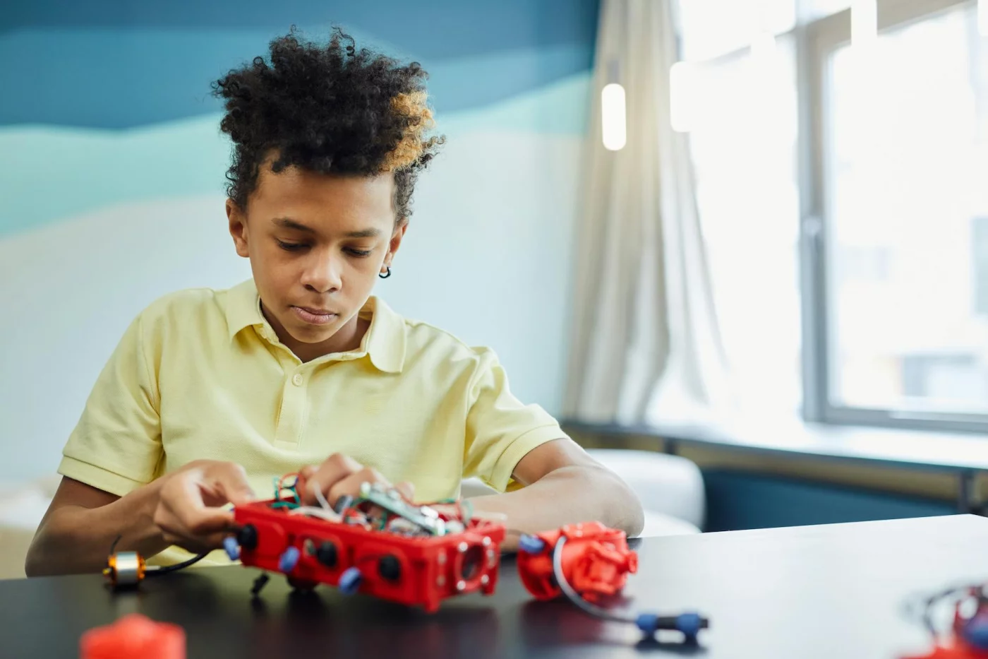 Growth Mindset vs Fixed Mindset in Studying Boy building a red robot indoors, showing growth mindset vs fixed mindset for students through hands-on learning