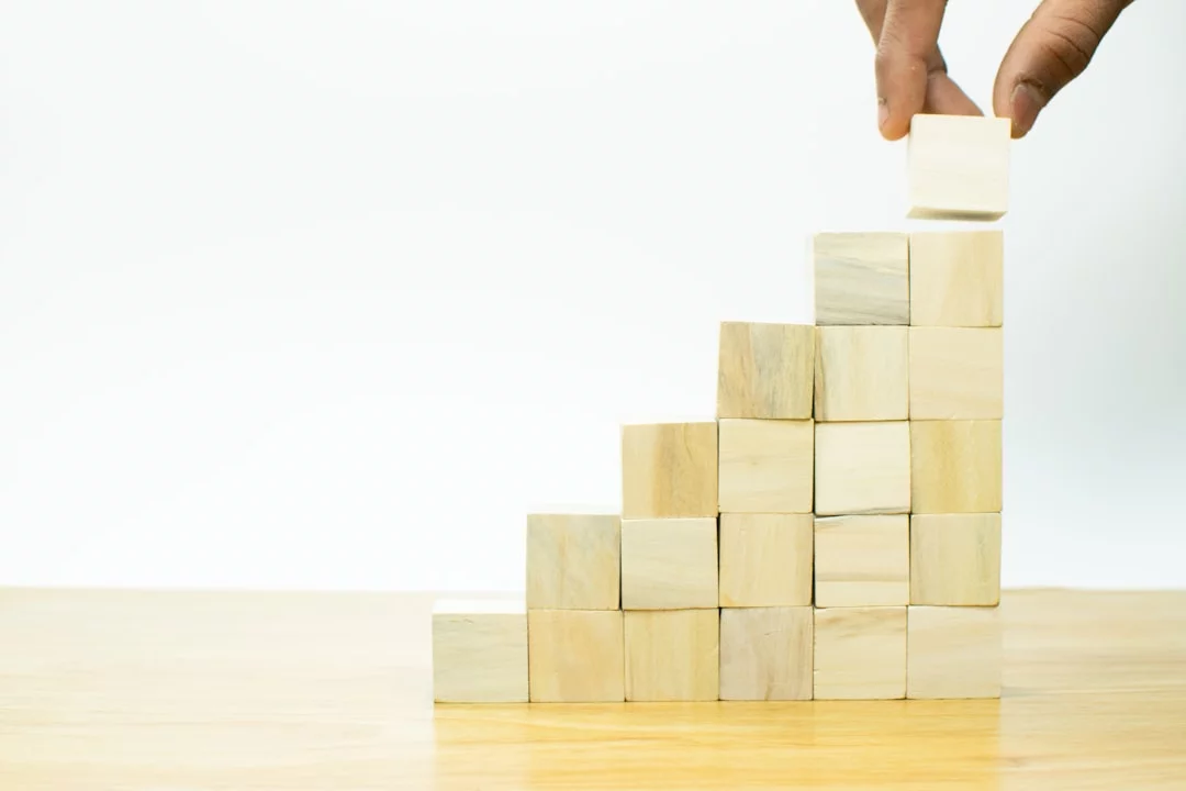 Habit Stacking: How to Pair New Habits With Old Ones Hand placing a block into a pyramid to illustrate habit stacking examples and how small routines build momentum