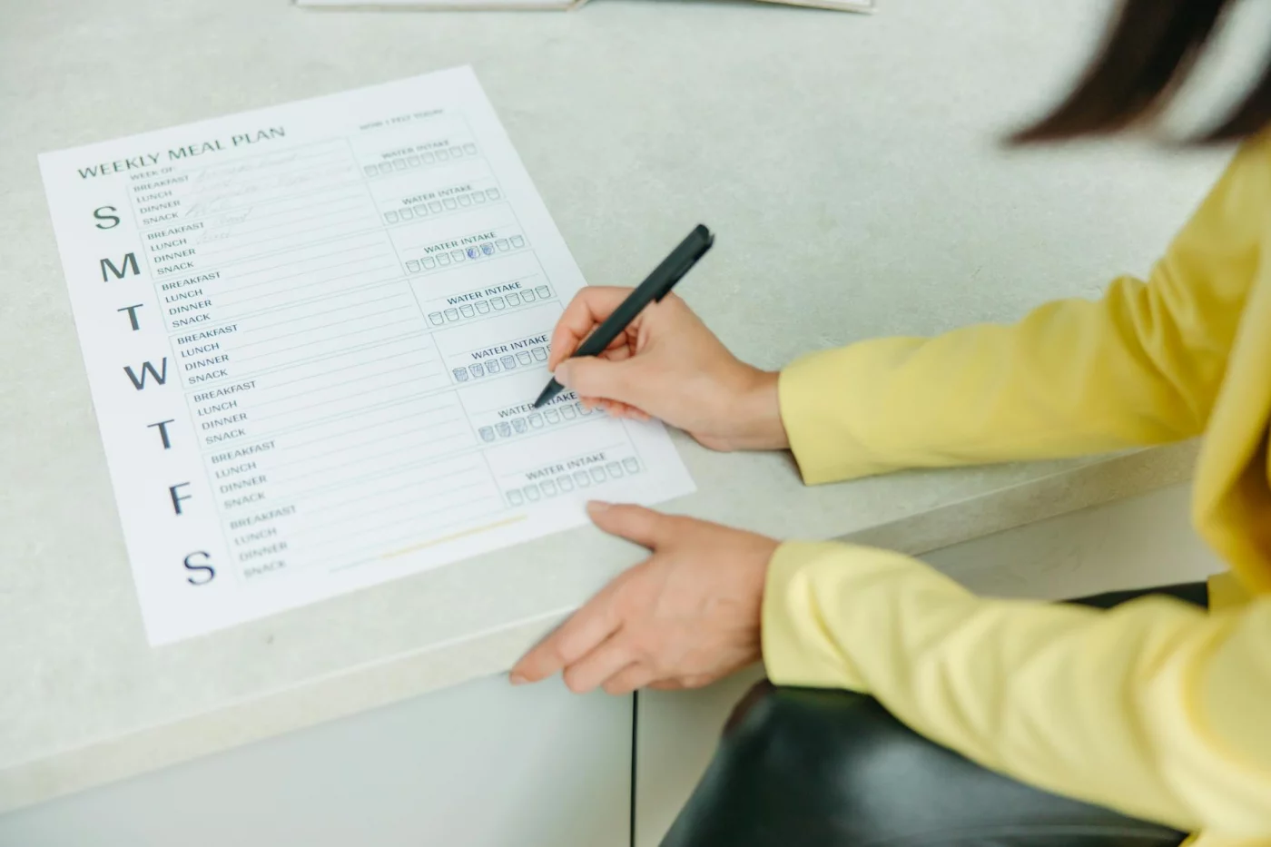 Habit Stacking: How to Pair New Habits With Old Ones Woman writing a weekly meal plan checklist, showing habit stacking examples for building a routine in 4 steps