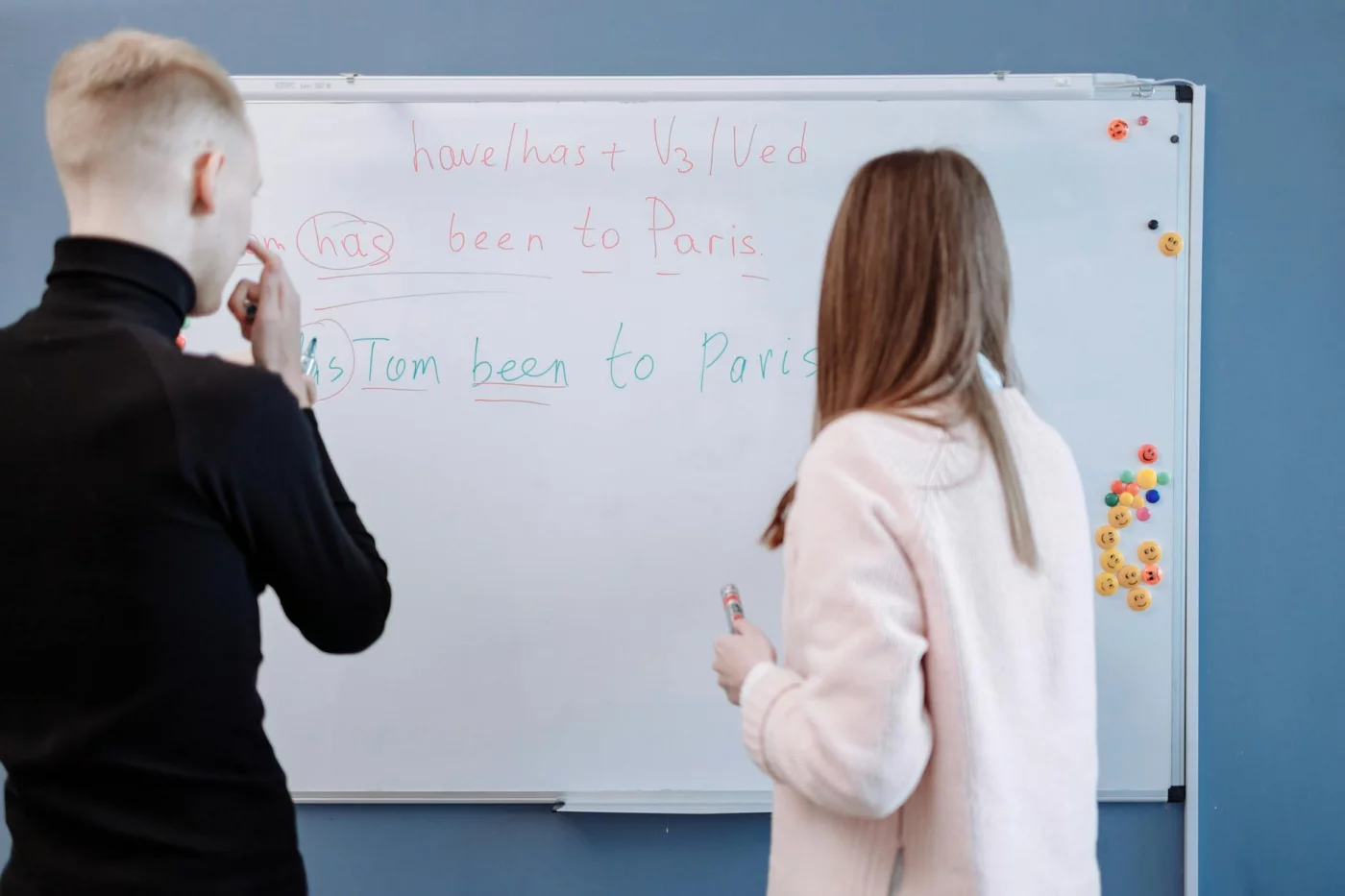 How Long Does It Take to Learn a Language? 7 Realistic Timelines by Level Students reviewing grammar at a whiteboard while tracking how long does it take to learn a language fluently