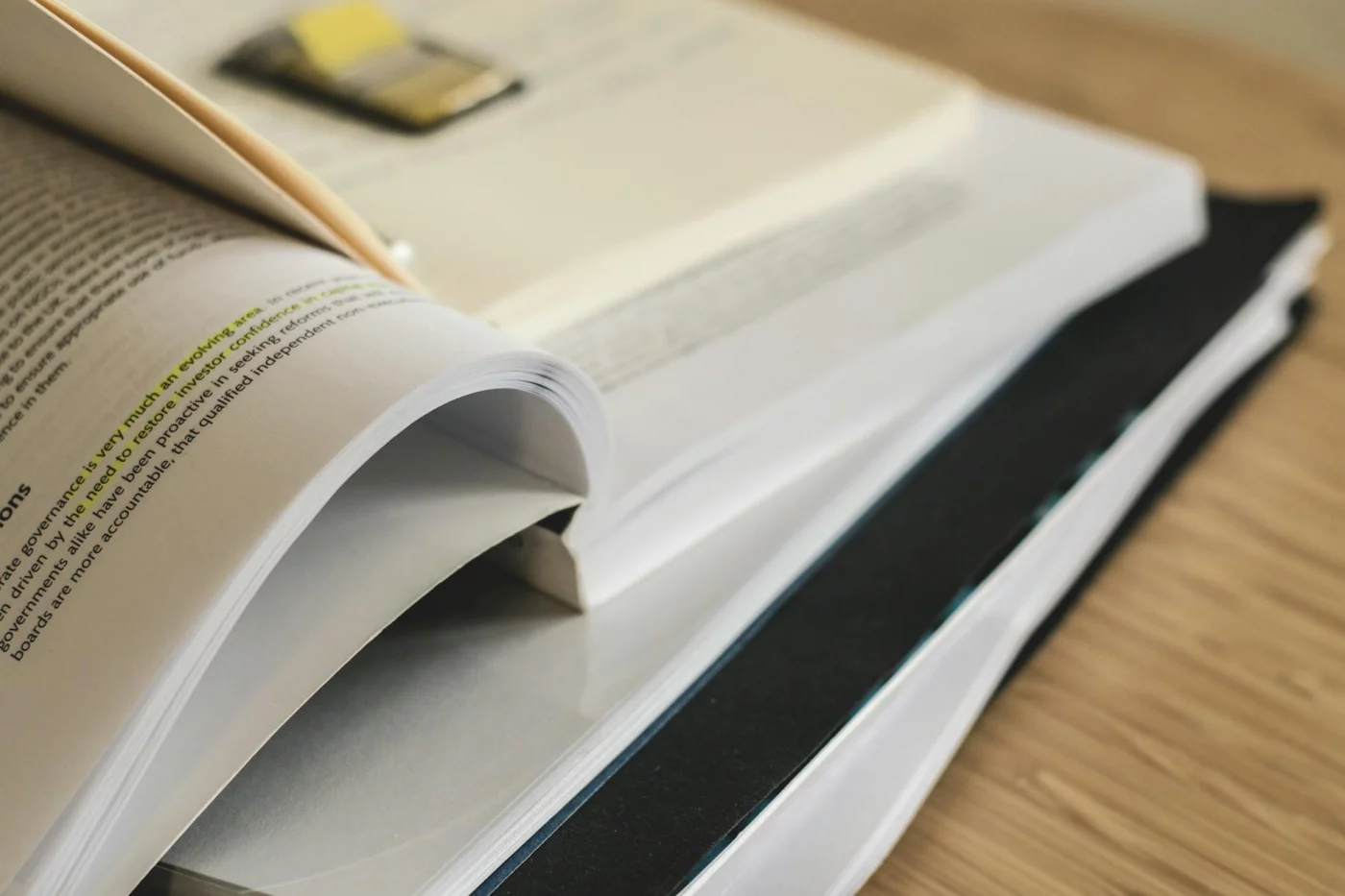 Open textbooks stacked on a table for a FAQ guide on how to annotate a textbook effectively