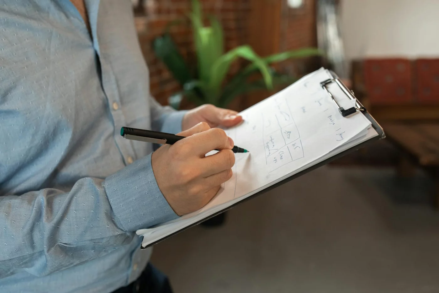 Person writing on a clipboard indoors, illustrating how to overcome procrastination through focused planning