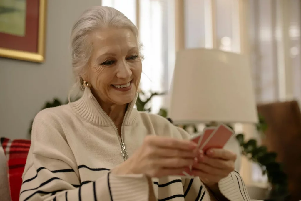 Senior woman smiling while playing cards indoors, illustrating how to prevent alzheimer's and dementia
