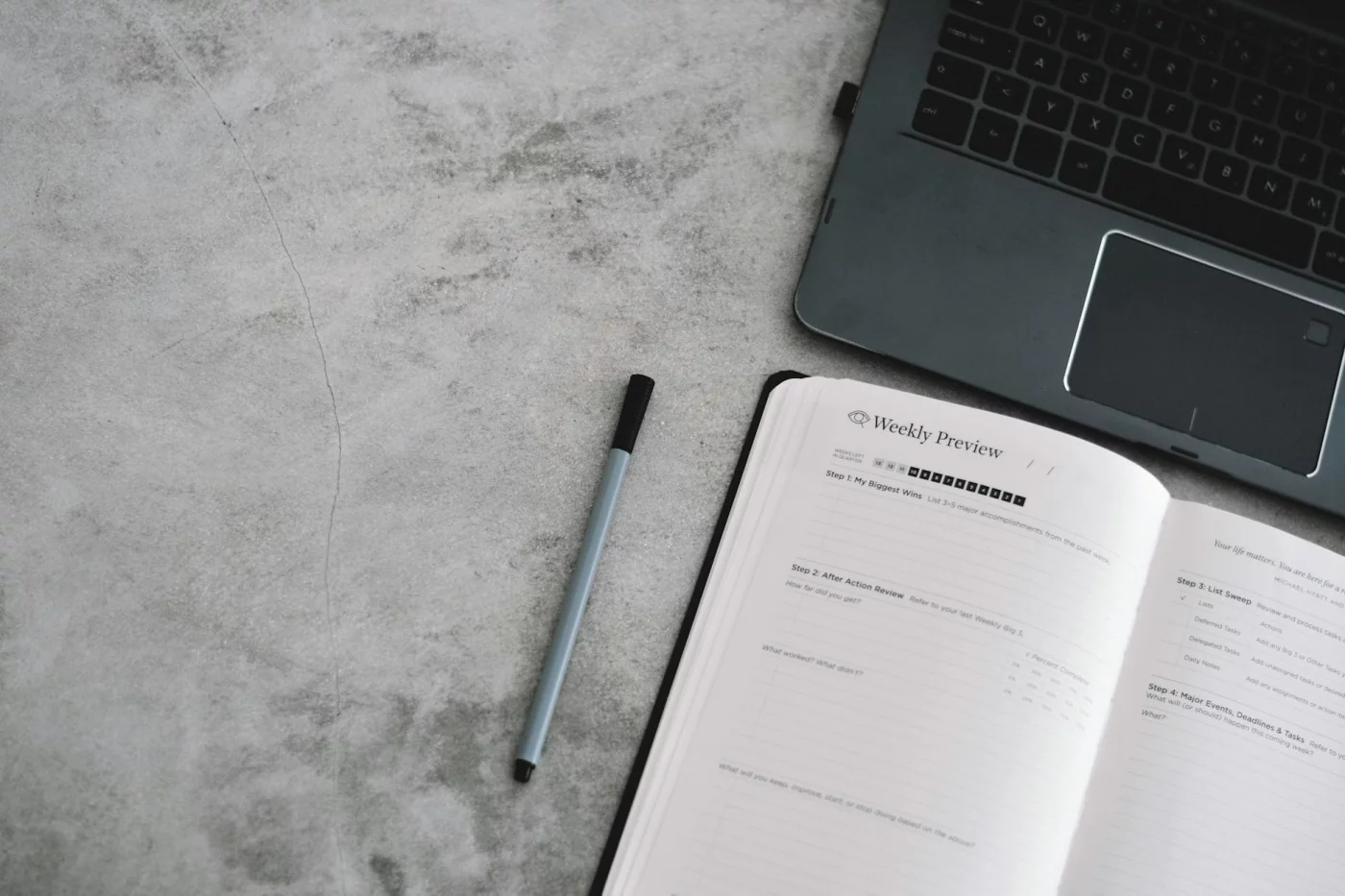 How to Read 50 Books a Year While Working Full-Time Planner, pen, and laptop on a minimalist desk illustrating the math behind how to read 50 books a year