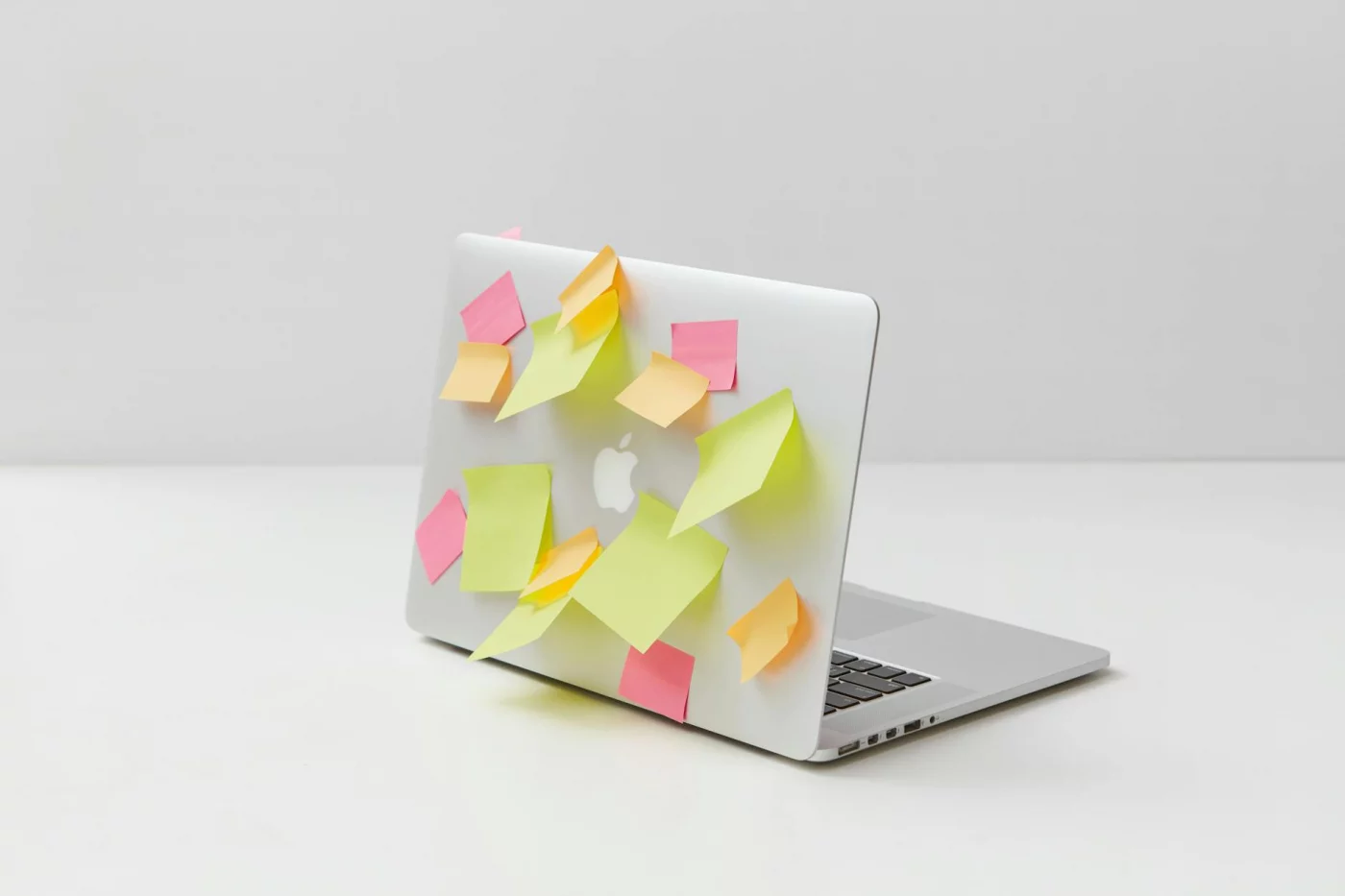 Laptop covered in colorful sticky notes on a white desk, showing how to read dense textbooks in real life