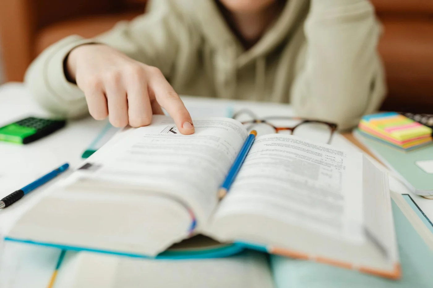 Student using quick reference notes to learn how to skim a textbook chapter while studying for exams indoors