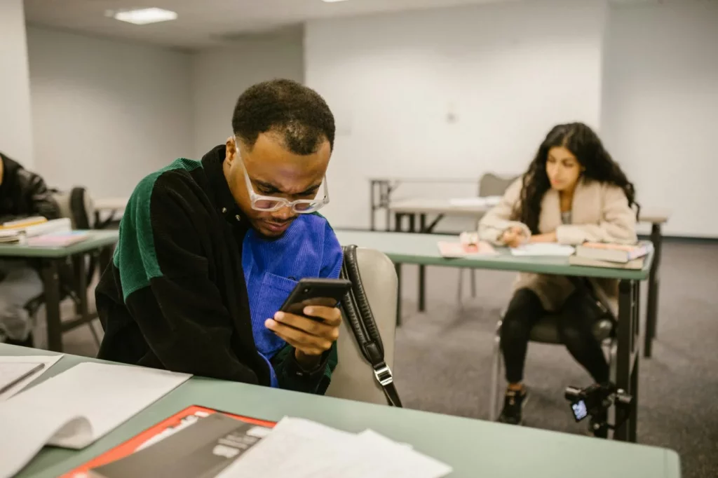 How to Stop Phone Addiction for Students Without Going Offline Classroom scene illustrating how to stop phone addiction for students as two college students check smartphones