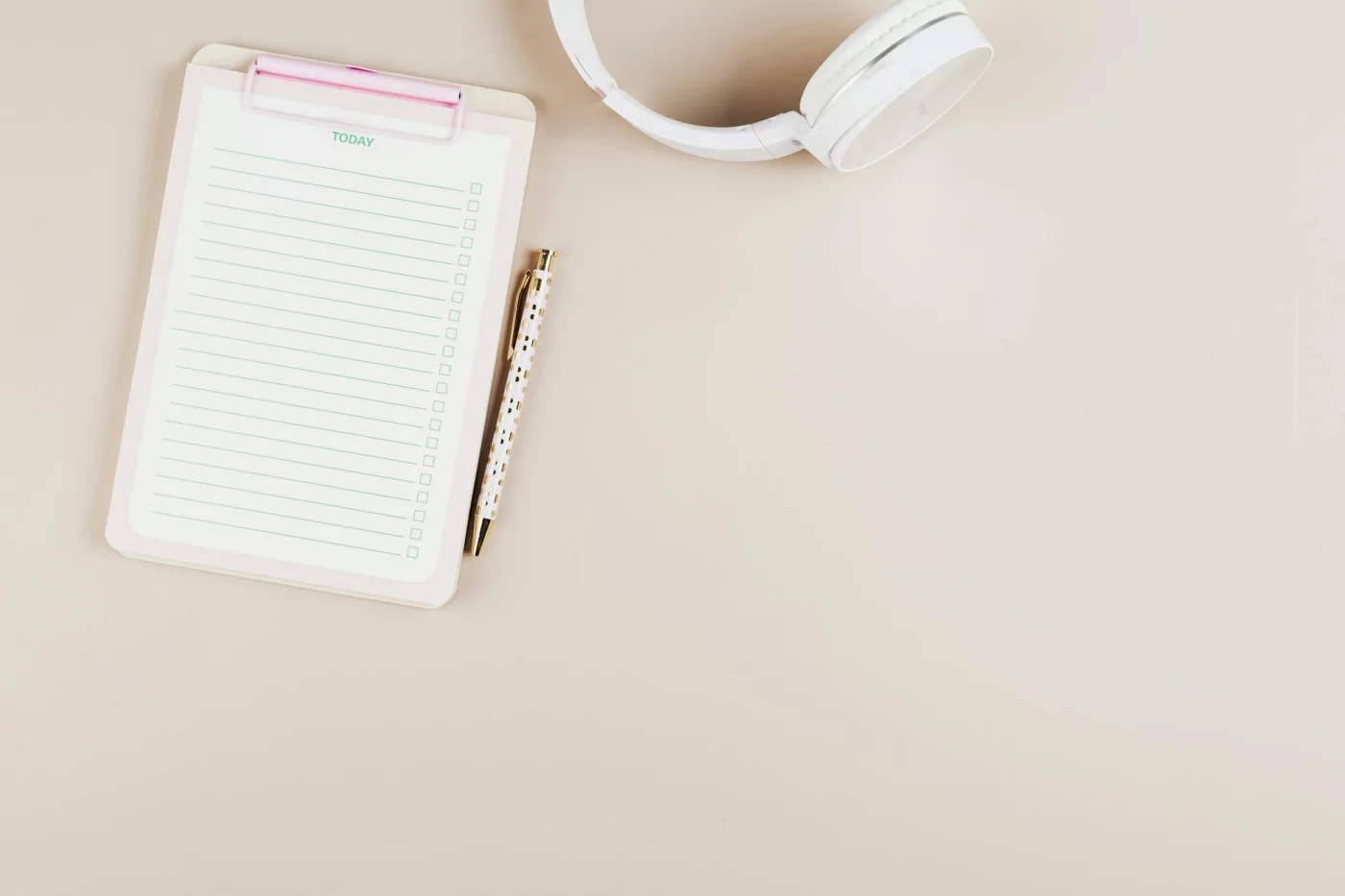 How to Study for Finals in a Week With a Realistic Plan Notepad, pen, and headphones on a white desk for planning how to study for finals in a week