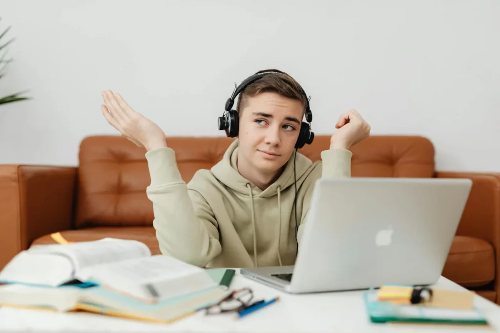 Young man using a laptop and headphones for online learning, showing how to study in a noisy house