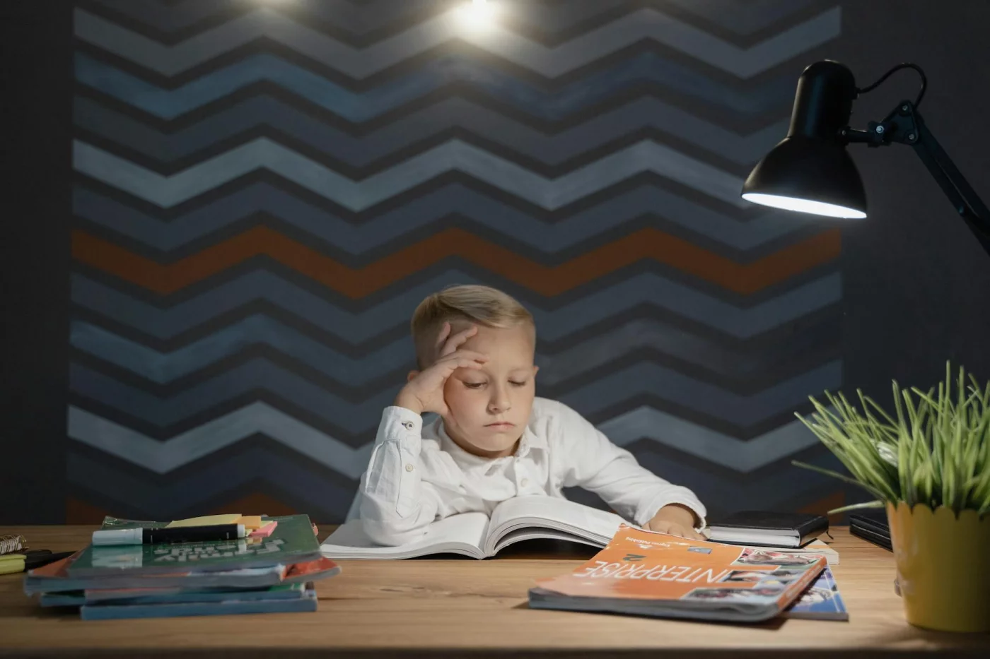 Boy studying at a desk under a lamp, showing how to study in a noisy house despite common home distractions