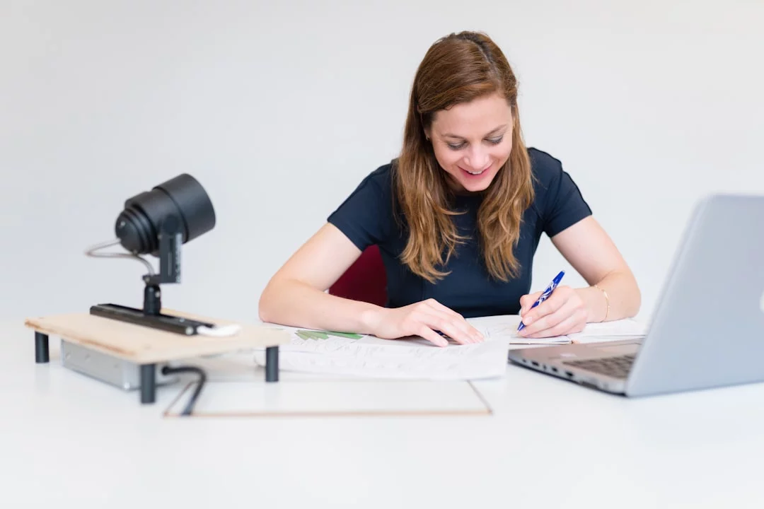 How to Take Notes from Video Lectures With 4 Smart Methods Student showing how to take notes from video lectures while writing in a notebook at her desk