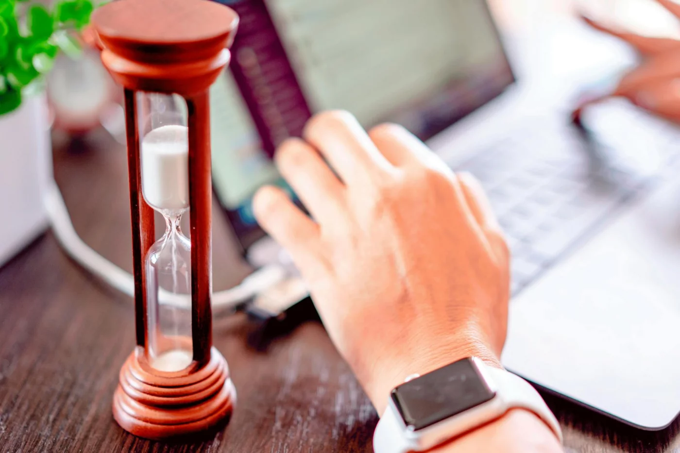Hand on a laptop beside an hourglass, showing what a 60-minute deep work block does and is time blocking good for adhd