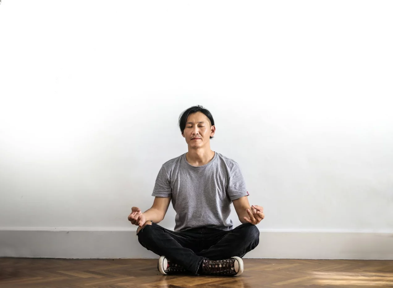 Mindfulness for People Who Can’t Sit Still Asian man practicing mindfulness exercises for anxiety on a wooden floor at home