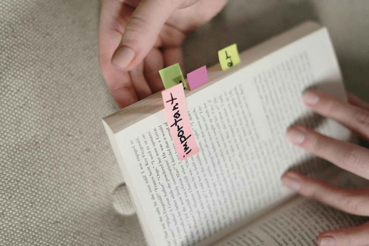 Hands holding a book with sticky tabs, illustrating open book exam tips for organized prep and quick reference