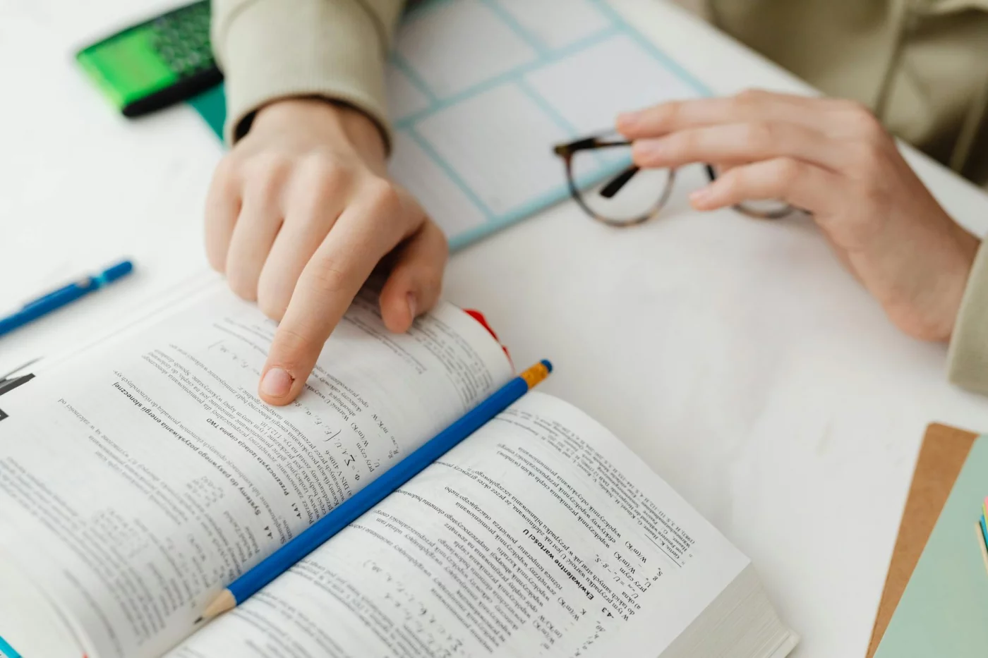 Student reviewing math problems with a textbook and pencil, applying open book exam tips at a desk