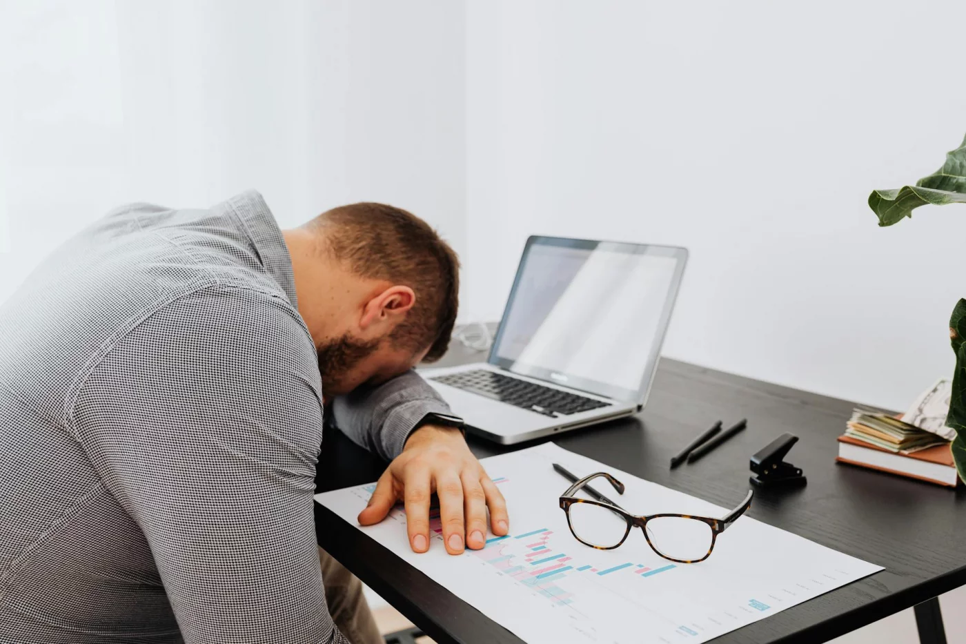 Workplace Burnout: 5 Stages and the Signs to Watch Worker at desk showing physical symptoms of burnout, including fatigue and stress during the workday
