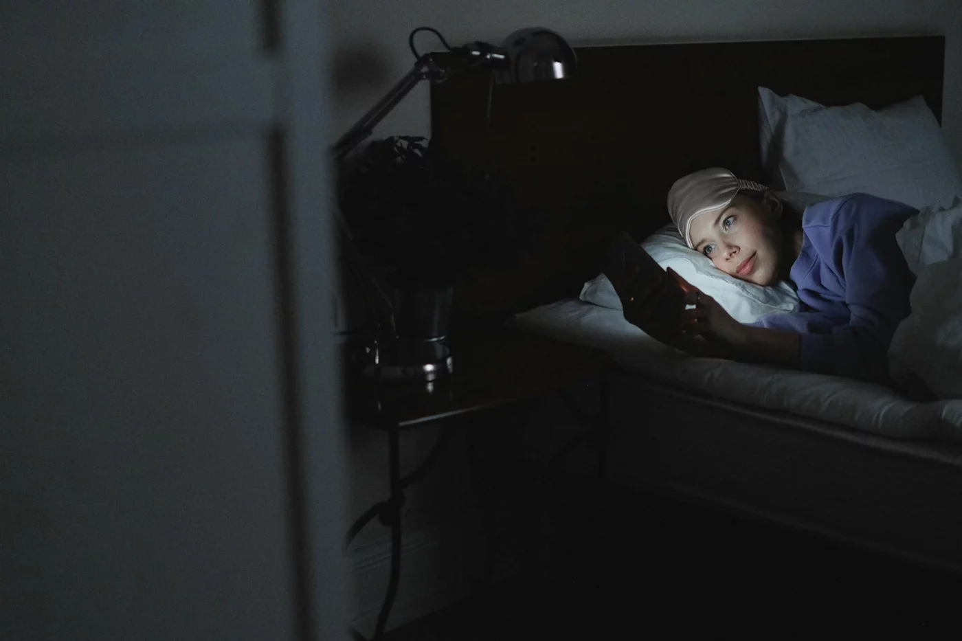 Woman in bed using a smartphone at night, illustrating the side effects of using phone at night