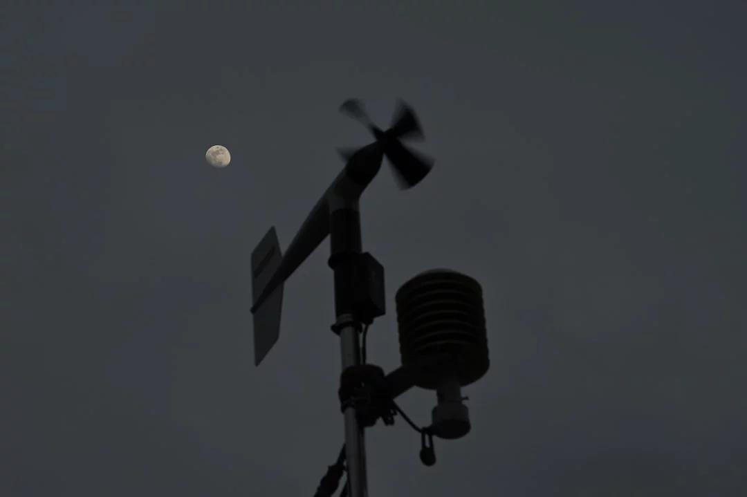Wind gauge silhouetted against the moon at dusk, symbolizing late-night triggers linked to sleep inertia