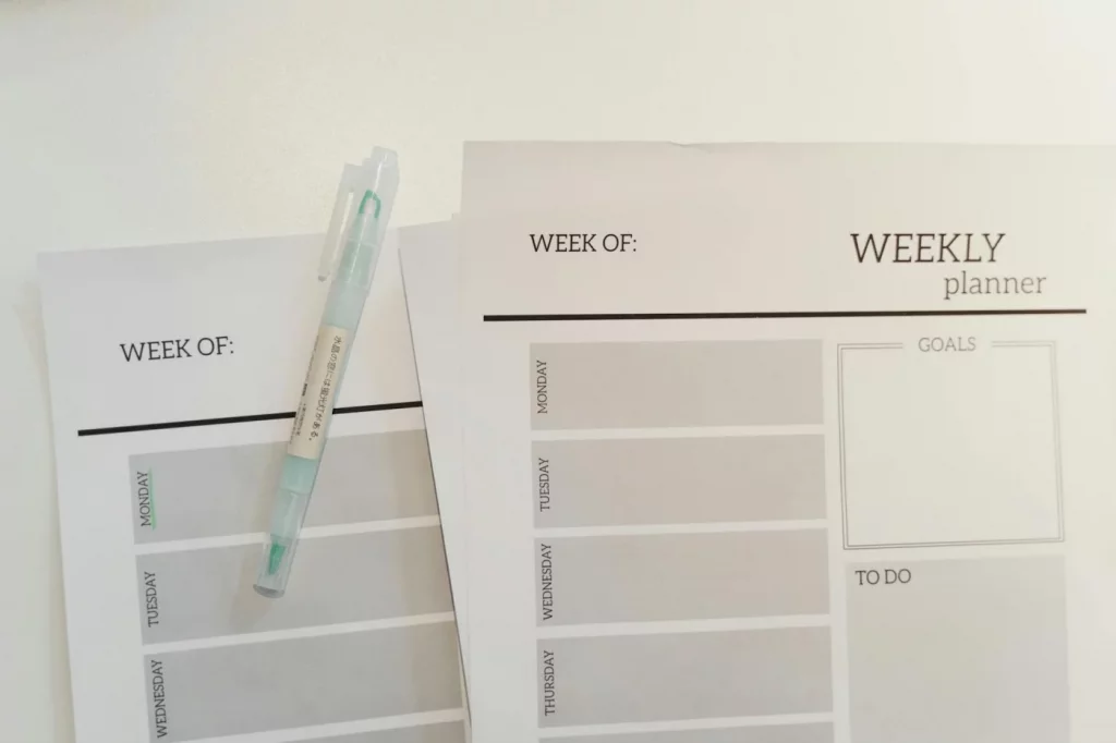 Undated weekly planner template sheets with a pen for flexible scheduling and weekly goal setting