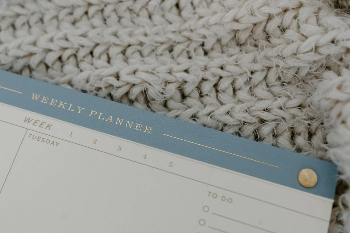 Simple undated weekly planner template resting on knitted fabric for a cozy, calendar-free planning setup