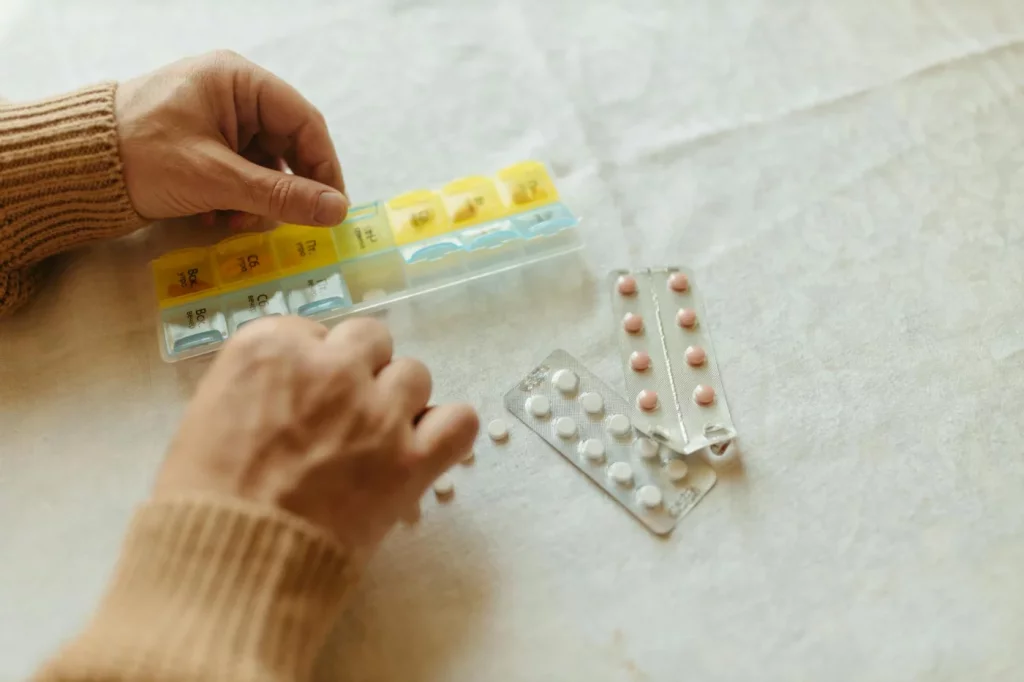 Memory Changes in Your 40s and 50s: What’s Normal vs Worrying Hands organizing tablets in a weekly pillbox, highlighting what causes memory loss and forgetfulness in older adults