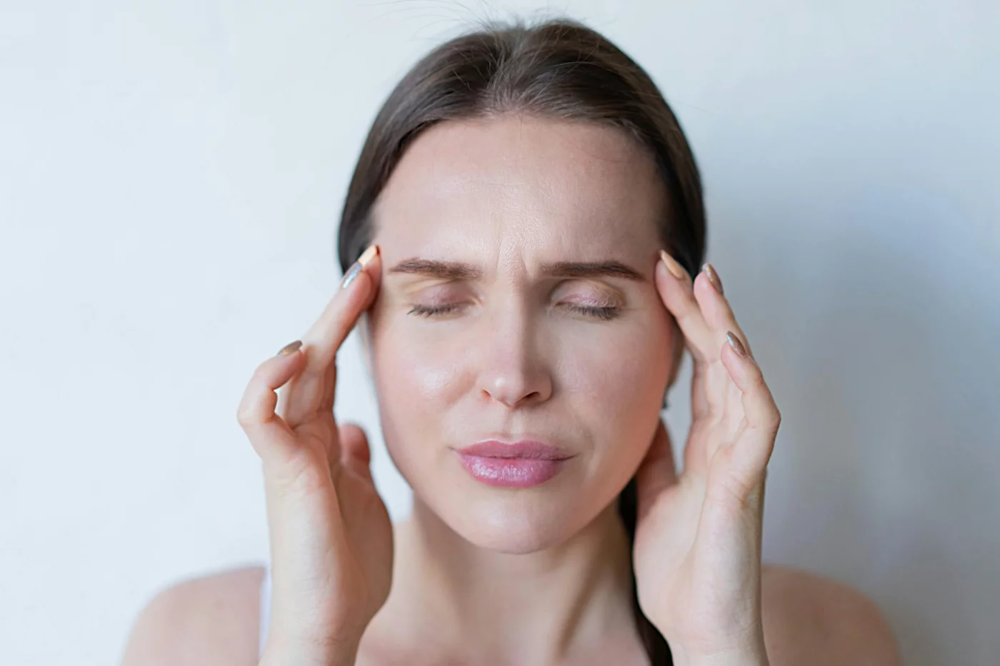 Memory Changes in Your 40s and 50s: What’s Normal vs Worrying Woman holding her temples with eyes closed, illustrating what causes memory loss and forgetfulness