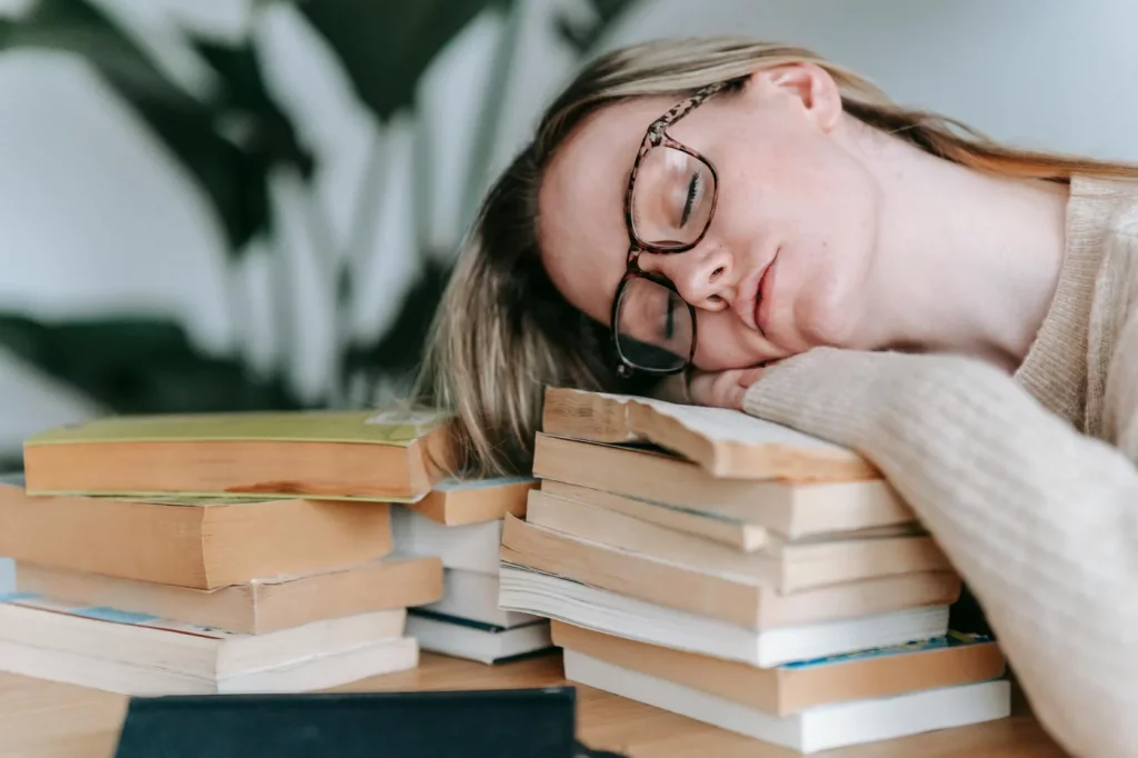 Student asleep on books, illustrating what is memory consolidation in psychology during study and rest