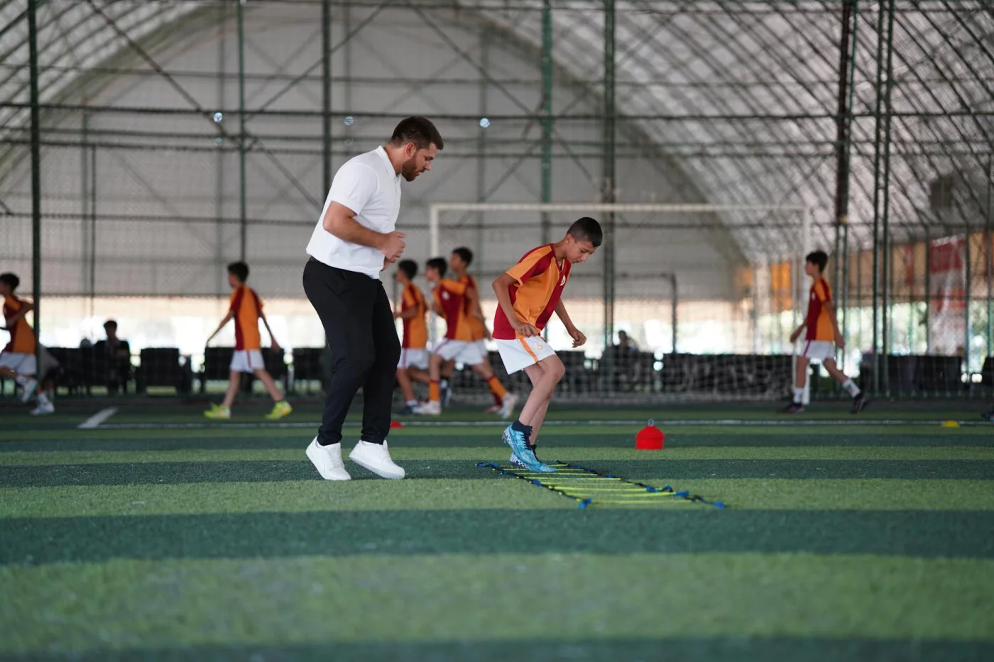 What Muscle Memory Really Means in the Brain Coach guides a young boy in indoor soccer practice, illustrating what is muscle memory in the brain through repetition