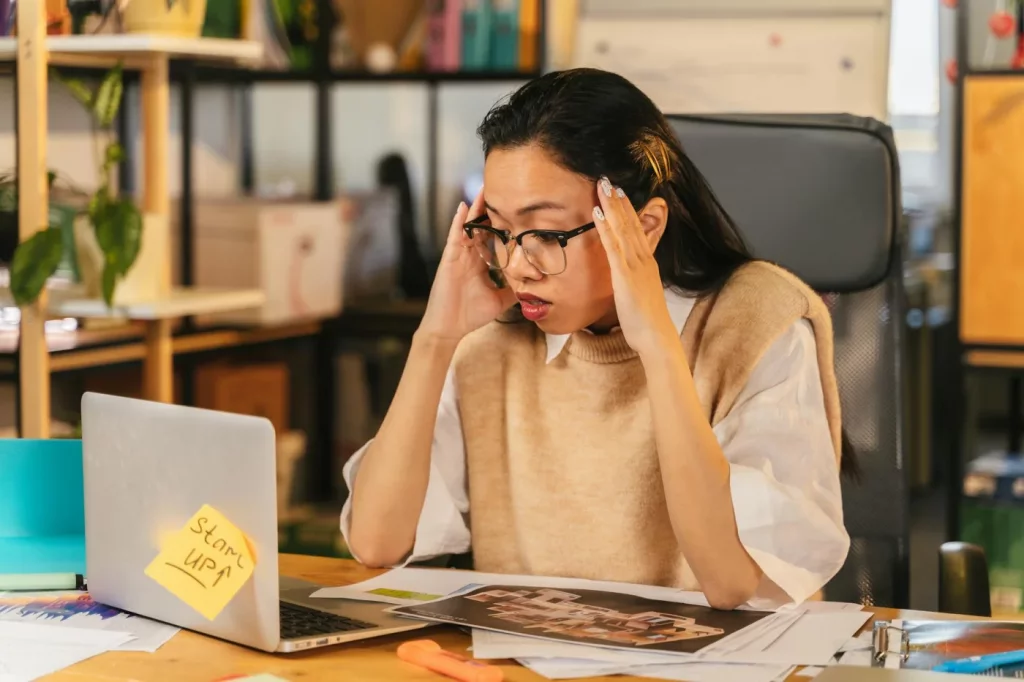 Amygdala Hijack Explained: What It Is and How to Calm It Stressed woman at a laptop in an office, illustrating what is the amygdala hijack during work pressure