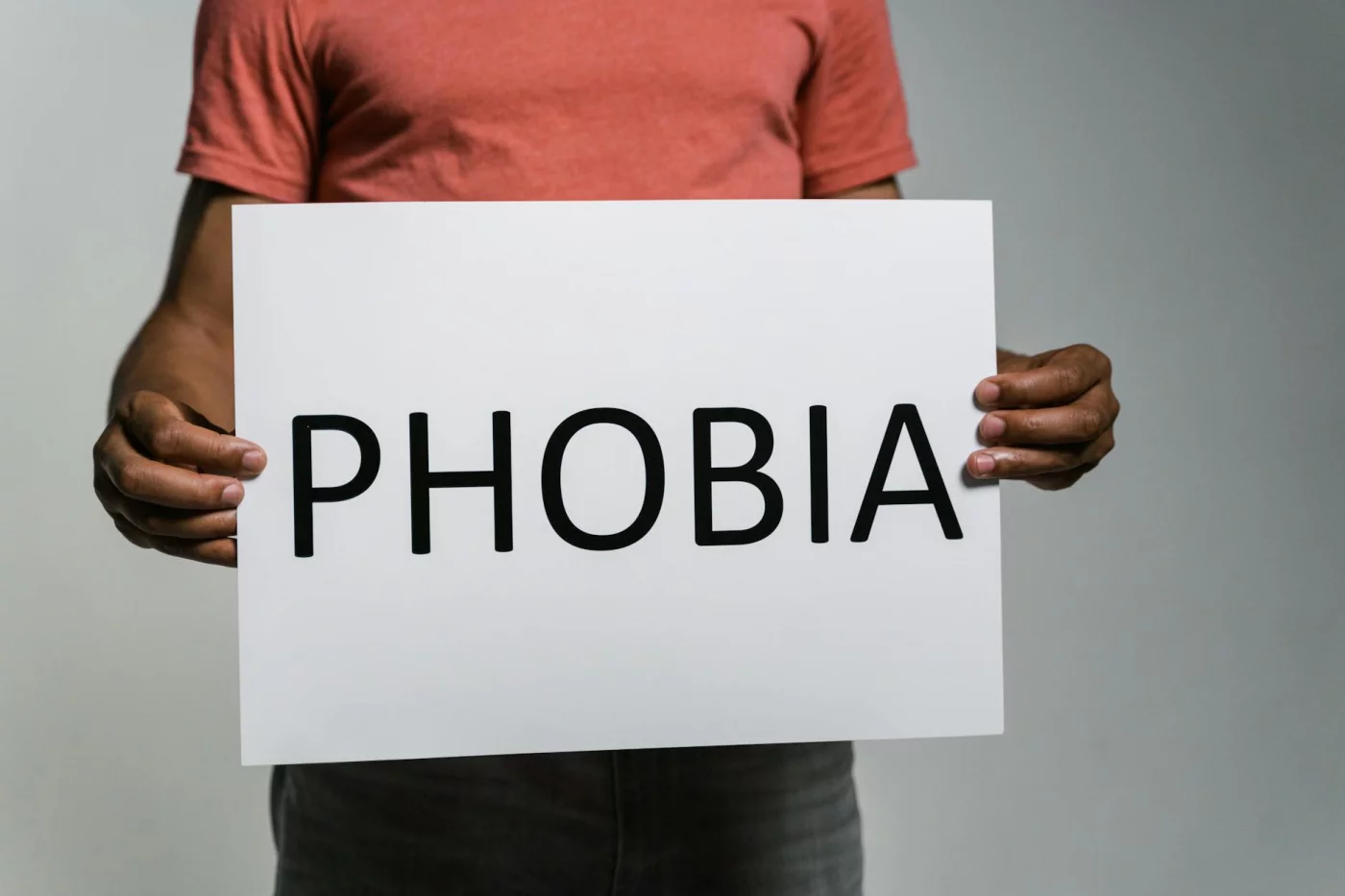 Amygdala Hijack Explained: What It Is and How to Calm It Adult holding a 'Phobia' sign to illustrate fear and anxiety in explaining what is the amygdala hijack