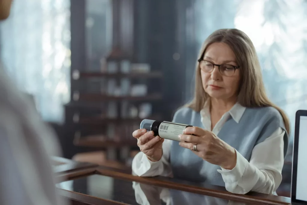 What Causes Memory Problems? The Main Causes by Age and Situation Senior woman reviews a medicine bottle at a pharmacy while asking what medications cause memory issues