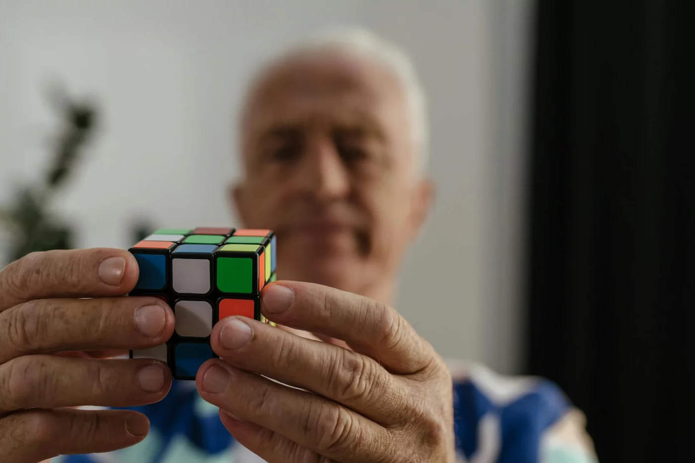 What Causes Memory Problems? The Main Causes by Age and Situation Senior man concentrating on a Rubik's Cube while exploring what medications cause memory issues