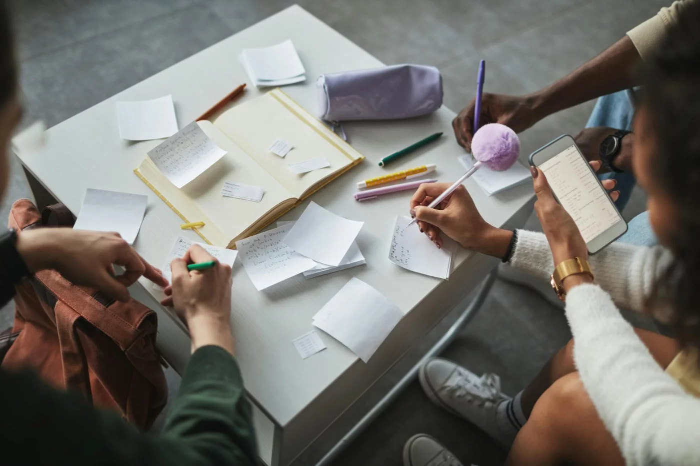 Zettelkasten for Students: 7 Smart Steps for Notes, Revision, and Writing Students studying together with notes, books, and phones, discussing the zettelkasten method for students