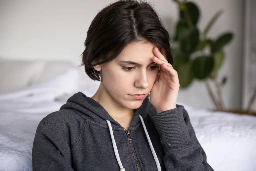 Young woman in a hoodie looking pensive indoors, reflecting on cognitive distortions examples linked to anxiety