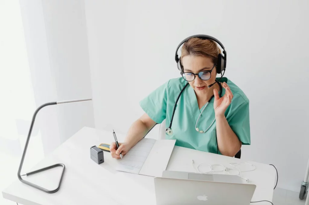 Doctor in scrubs takes notes during a telehealth consult about flow neuroscience clinical trials